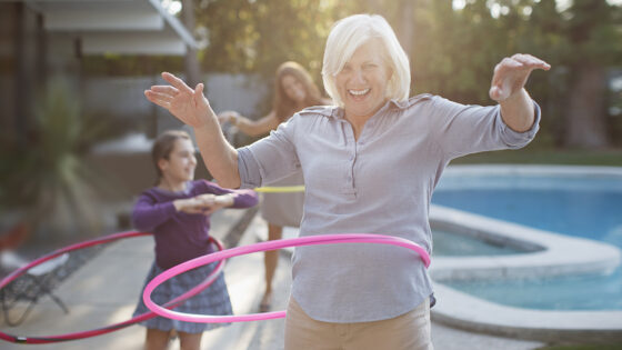 Older woman hula hooping in backyard